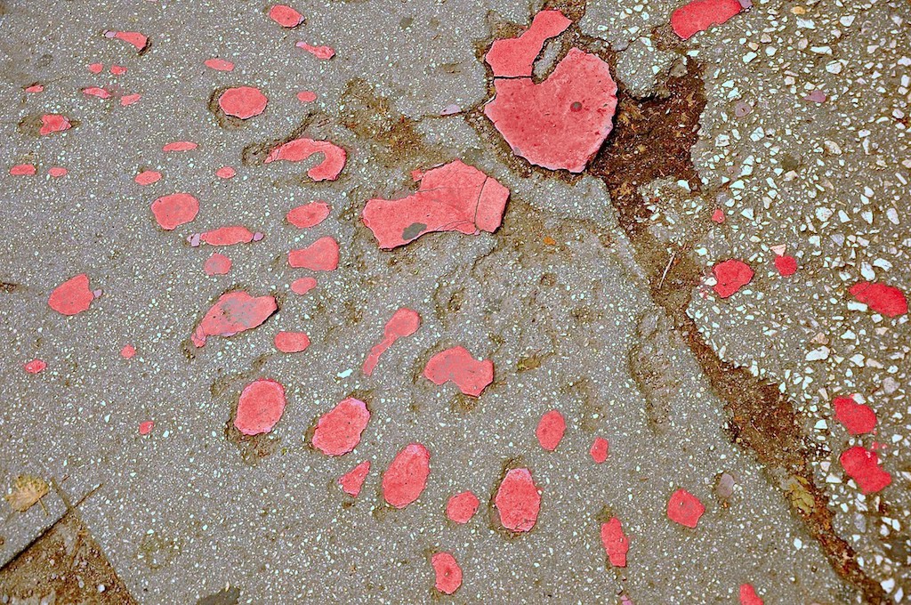 photo of a mortar blast in the sidewalk filled in with red resin, which forms a unique pattern